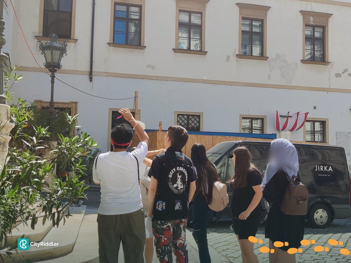 A school group looks up at a building during a riddle tour in Vienna